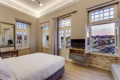 a bedroom with a bed and a tv and windows at 1924 suites in Chania Town