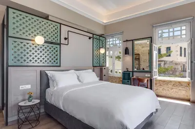 a bedroom with a large white bed and windows at 1924 suites in Chania Town