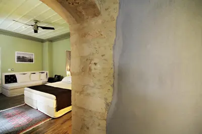 a bedroom with a bed and a stone wall at Elia Fatma Boutique Hotel in Chania Town