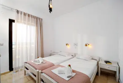 a white bedroom with two beds and a window at Matzi Hotel Apartments in Gerani Chanion