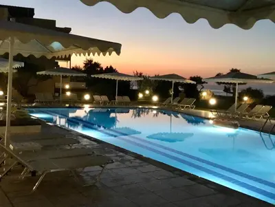 a swimming pool at night with chairs and umbrellas at Matzi Hotel Apartments in Gerani Chanion