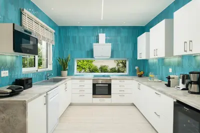 a kitchen with white cabinets and blue walls at Seaview Garden Villa - Heated Pool & Sauna in Stalos