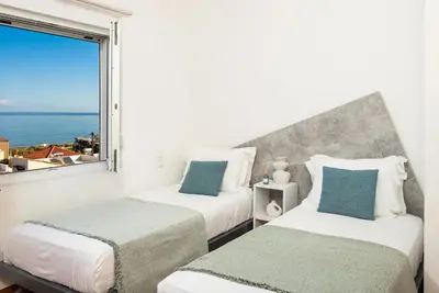 two beds in a room with a large window at Seaview Garden Villa - Heated Pool & Sauna in Stalos