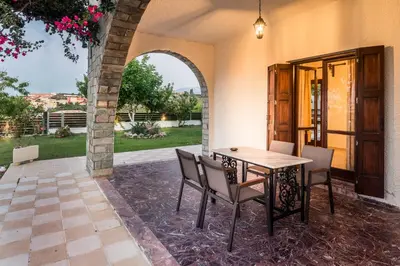 a patio with a table and chairs and an archway at Villa Merabello in Agia Marina Nea Kydonias
