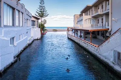 two people swimming in a canal between buildings at Kalyves Maisonette Bougainvillea in Kalyves