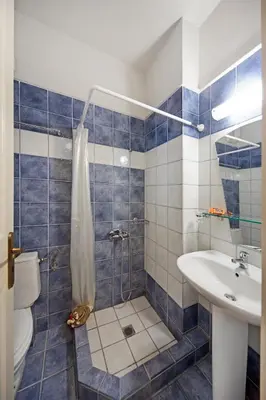a blue tiled bathroom with a shower and a sink at Sody Magnificent Bay View in Chania Town