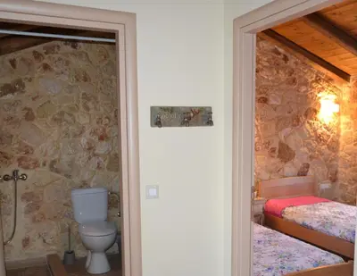 a bathroom with a toilet and a bedroom with two beds at Rumpis Traditional House in Kambánion