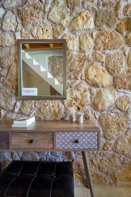 a mirror on a stone wall with a wooden table at Dimitra's House in Old Town in Chania Town