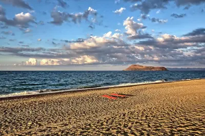 a red bench on a sandy beach near the ocean at Gianna's House in Gerani Chanion