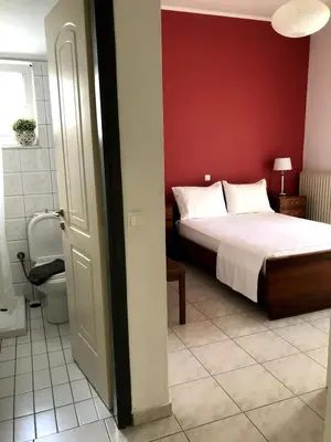a bedroom with a bed and a red wall at Rosy's House with all Amenities near Chania in Chania Town
