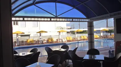 a view of a swimming pool from a restaurant with tables and chairs at Elektra Beach Hotel in Kalamaki Chanion
