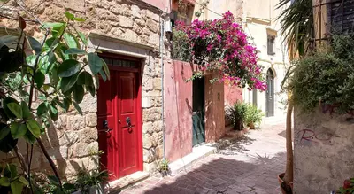 a red door on the side of a building with flowers at Emmanouil’s House in Chania Town