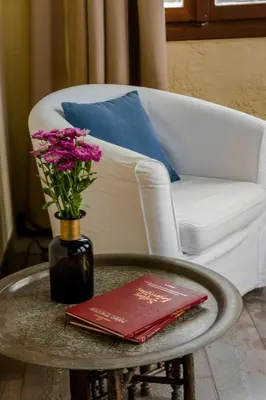 a vase of flowers and a book on a coffee table at Alcanea Boutique Hotel in Chania Town