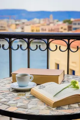 a table with two books and a cup of coffee at Alcanea Boutique Hotel in Chania Town