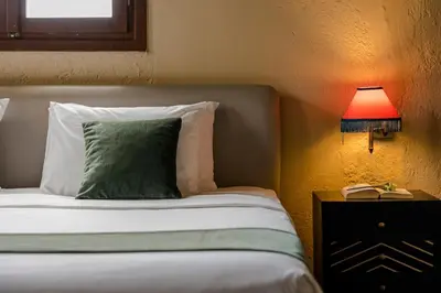 a bed with a green pillow and a table with a lamp at Alcanea Boutique Hotel in Chania Town