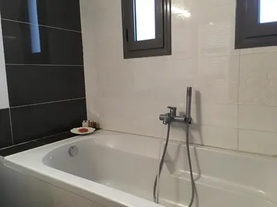 a white bath tub with a shower in a bathroom at Stellar Beachhouse in Gerani Chanion
