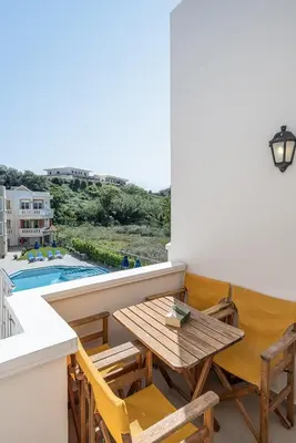 a balcony with a table and chairs and a pool at Artemis Apartments in Stalos