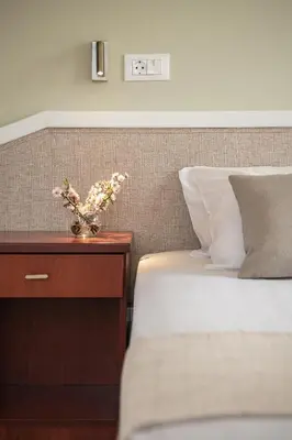 a bed with a vase of flowers on a night stand at Artemis Apartments in Stalos