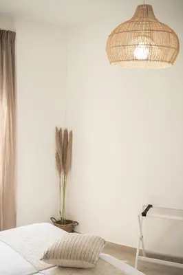 a white bedroom with a bed and a pendant light at Artemis Apartments in Stalos