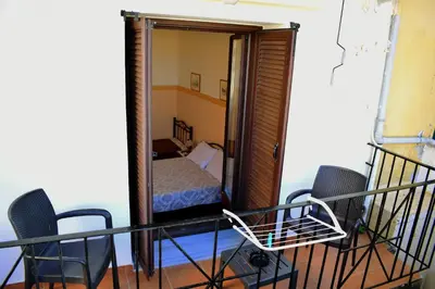 a room with a balcony with a bed and chairs at Stoa Rooms in Chania Town