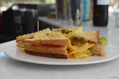 a sandwich and chips on a white plate at Kiwi Apartments in Kato Daratso