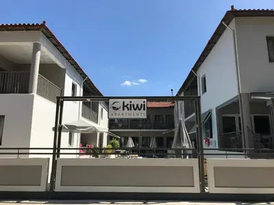 a white building with a kiwi sign on it at Kiwi Apartments in Kato Daratso