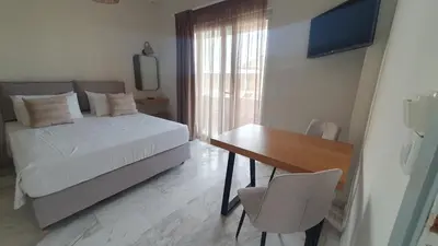 a bedroom with a bed and a desk and a television at Oliva Beach Hotel in Maleme