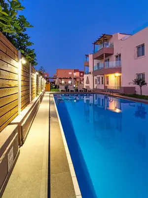 a large swimming pool with lights on the side of a building at Oliva Beach Hotel in Maleme
