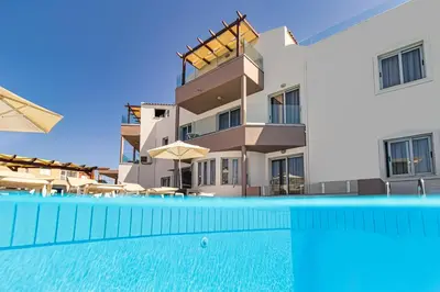 a building with a swimming pool in front of a building at Oliva Beach Hotel in Maleme