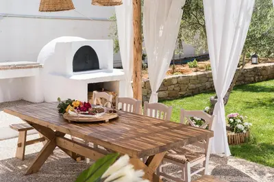 a picnic table with a pizza oven in a backyard at San Pietro Villa in Plataniás