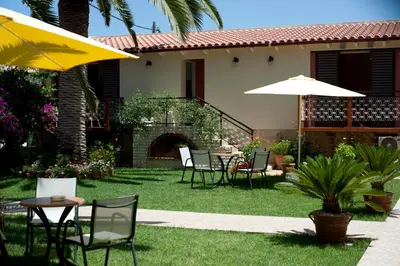 a patio with chairs and tables and an umbrella at Nikolas Suites in Kato Daratso