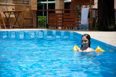 a woman is in a swimming pool with yellow paperippers at Nikolas Suites in Kato Daratso