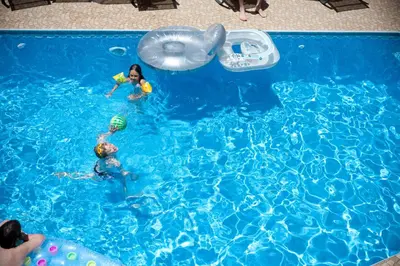 two children playing in a swimming pool with an inflatable at Nikolas Suites in Kato Daratso
