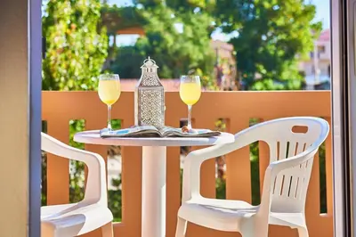 two glasses of wine on a table with two chairs at Solon Apartments in Maleme