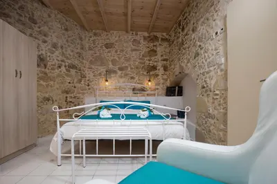 a bedroom with a bed and a stone wall at Trigono Luxury House in Kissamos
