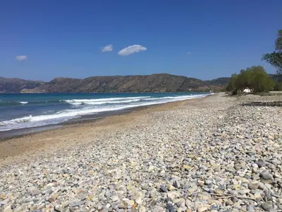 a rocky beach with the ocean and mountains in the background at WeCrete Apartments in Drapaniás