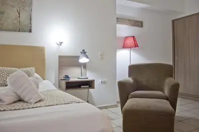 a bedroom with a bed and a chair and a lamp at Hotel Christina in Chania Town