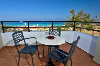 a table and chairs on a balcony with the ocean at Nikos Apartments in Falasarna