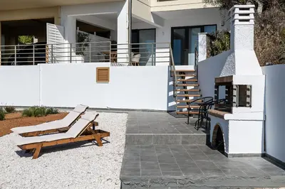 a patio with a bench and a fire place at Blue Island Luxury Apartment in Kato Daratso