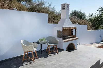 a patio with a fireplace and two chairs and a table at Blue Island Luxury Apartment in Kato Daratso