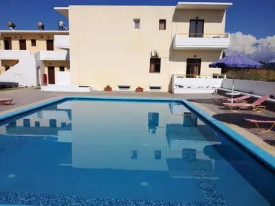 a house with a swimming pool in front of a building at Karmi Apartments in Kolymvari