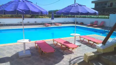 a swimming pool with two chairs and two umbrellas at Karmi Apartments in Kolymvari