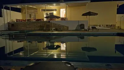 a pool with chairs and umbrellas reflecting in the water at Karmi Apartments in Kolymvari