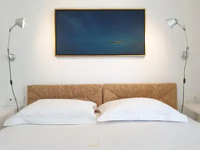 a bed with two pillows and a picture on the wall at Fos Villa, a Luxe House with Private Heated Pool in Galatás