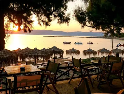 a view of a beach with tables and chairs and boats in the water at Aphrodite Beach in Kissamos