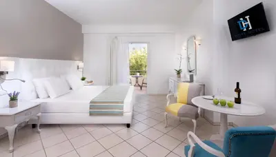 a white bedroom with a white bed and a table at Dore Boutique Hotel in Agia Marina Nea Kydonias