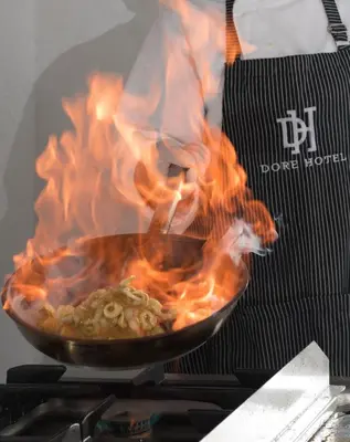 a person cooking food in a pan on a stove at Dore Boutique Hotel in Agia Marina Nea Kydonias