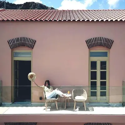 a woman sitting on the balcony of a house at Avra Apartments Kolymbari Harbour in Kolymvari