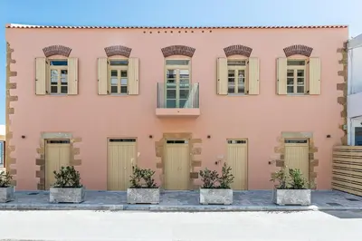a pink building with doors and windows at Avra Apartments Kolymbari Harbour in Kolymvari