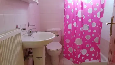 a bathroom with a sink and a toilet and a pink shower curtain at Irene's studio in chania in Chania Town